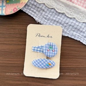 Detail of blue plaid hair clips with cherry beads and embroidery on a display card