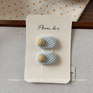Detail of light blue and yellow checkered fabric hair clips on artistic background