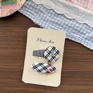 Detail of cute black and white plaid fabric hair clips with colorful cherry decorations