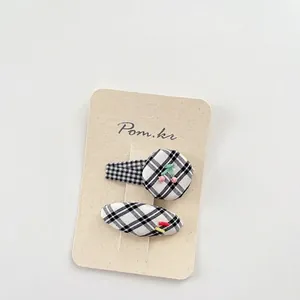 Set of two black and white plaid hair clips featuring cute cherry bead accents on card