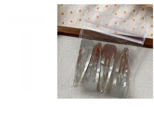 Detailed view of four silver metal teardrop hair clips in clear plastic packaging