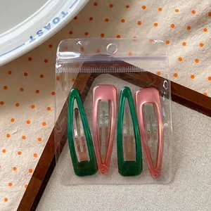 Detailed set of four waterdrop hair clips in green and pink colors inside clear packaging