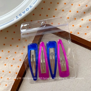 Detail of 4-piece teardrop hair clips in neon blue and pink inside retail packaging