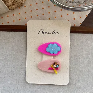 Details von rosa Stoff-Haarklammern mit blauer Wolke und gelber Schleife auf Karte