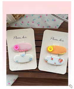 Vue détaillée de barrettes en tissu floral avec boutons décoratifs sur carte blanche