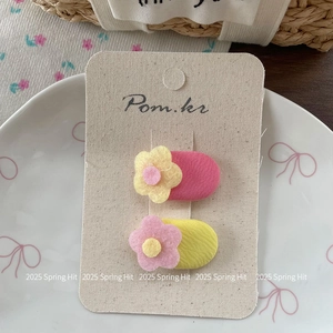 Close-up of floral fabric hair clips in pink and yellow set on decorative card