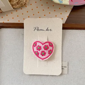 Detail of pink heart-shaped embroidery patch with floral patterns on display card
