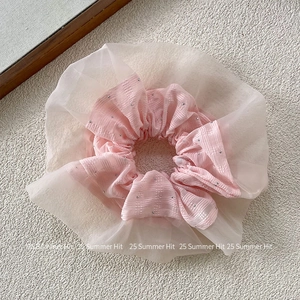 Dettaglio di un elastico per capelli a scacchi rosa con tulle crema e perline metalliche