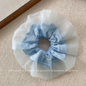 Dettaglio dell'elastico per capelli in organza blu con pieghe e piccoli strass lucidi