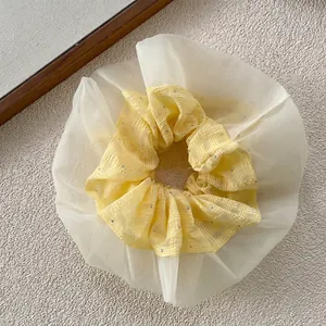 Dettaglio dell'elastico per capelli in rete gialla con strass argentati e trama morbida