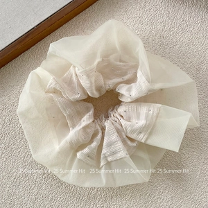 Dettaglio dell'elastico in organza crema con trama a scacchi e strass scintillanti
