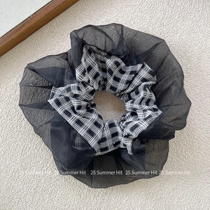 Dettaglio dell'elastico scrunchie in organza nera con tessuto interno a quadri bianchi e neri