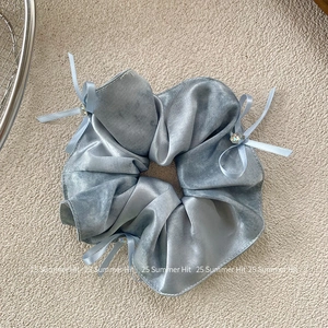 Detail of grey-blue satin scrunchie featuring delicate bows and sparkling gemstones