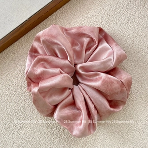 Detailed texture of dusty rose velvet scrunchie with soft sheen and pleated fabric
