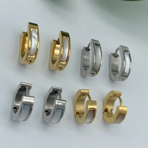 Détail de boucles d'oreilles huggie en or et argent avec incrustations de nacre