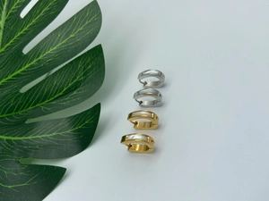 Détail de boucles d'oreilles créoles en acier doré et argenté avec nacre blanche