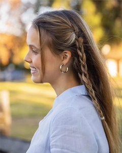 Classic gold hoop earrings worn by a model in warm natural outdoor sunlight