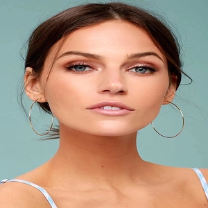 Gros plan d'un mannequin portant de grandes créoles dorées en acier titane minimaliste