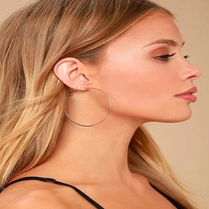 Gros plan d'une grande boucle d'oreille en acier titane or rose portée par un mannequin