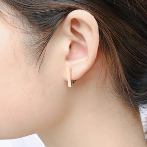 Close-up of minimalist rose gold rectangular geometric drop earrings worn by a model
