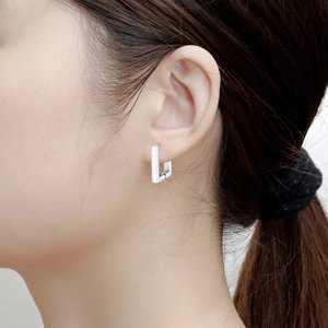 Close-up of minimalist silver geometric earring on model showing polished finish