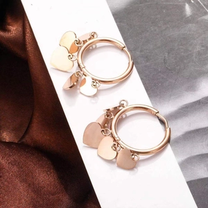 Detail of rose gold hoop earrings with polished heart charms on a display card