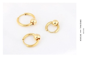 Detailed close-up of gold hoop earrings featuring sliding metal beads on a textured surface