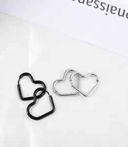 Detail von minimalistischen herzförmigen Creolen in poliertem Silber und Schwarz