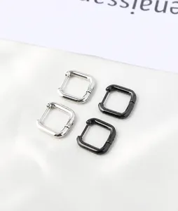 Close-up of black and silver square hinged hoop earrings made of titanium steel