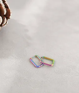 Detail of minimalist rainbow gradient titanium steel rectangle hoop earrings on a white surface