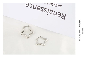 Polished stainless steel star-shaped earrings on minimal background with magazine