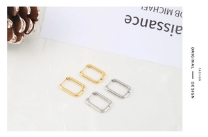 Macro shot of minimalist gold and silver rectangular hoop earrings with a mirror finish