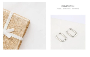 Macro shot of silver rectangular stainless steel earrings next to a gold glitter gift box