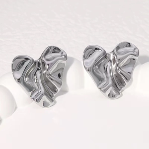 Macro shot of silver heart studs with textured molten lava metal finish for women