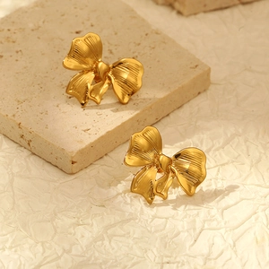 Détail de boucles d'oreilles nœud plaqué or 18 carats avec texture sur marbre