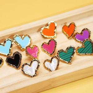Exquisite heart-shaped crystal oil drip earrings in multiple colors on a wood tray