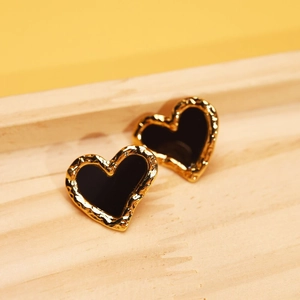Detail of heart stud earrings with golden hammered edges and black enamel finish