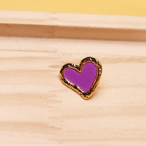 Macro shot of heart earrings with purple enamel and hammered golden metal texture