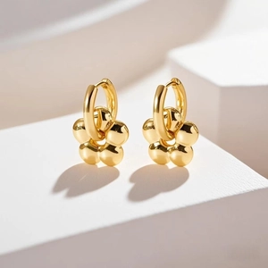 Minimalist 18K gold plated stainless steel flower earrings displayed on a white stone base