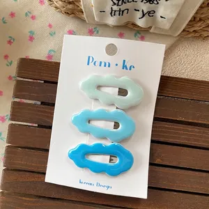 Close-up of three wavy cloud hair clips in light blue and cyan on a display card
