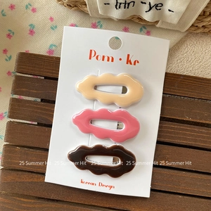 Close-up of three wavy hair clips in cream, pink and brown on a Korean display card