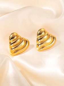 Détail de boucles d'oreilles cœur dorées avec texture ondulée sur fond de soie de luxe