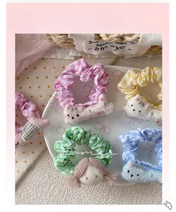 Detail of four colorful checkered scrunchies with cute 3D cartoon charms in a porcelain bowl