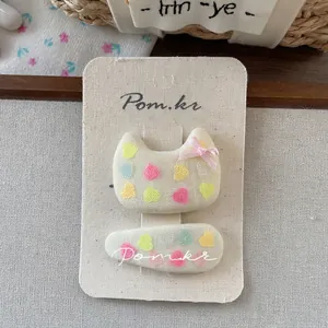 Detail of fabric hair clips with colorful heart patterns and a pink ribbon bow on card