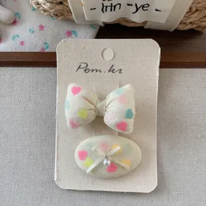 Detail of sweet cream fabric heart-print hair clips with bow and pearl on display