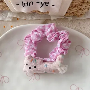 Detailed view of a pink plaid hair scrunchie with cute cat and mesh bow in porcelain plate