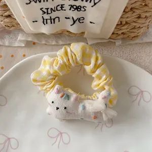 Detail of yellow plaid scrunchie with cute white fabric cat and rainbow embroidery