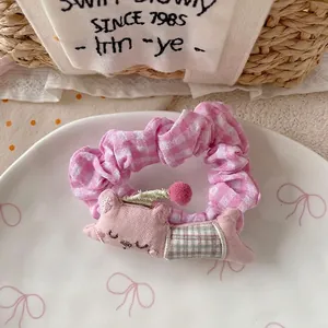 Detailed shot of pink plaid scrunchie with cute 3D cartoon animal mascot in a white plate
