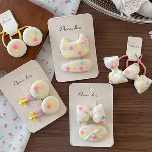 Sweet heart-print bow hair clips and elastic hair ties set on a rustic wooden background