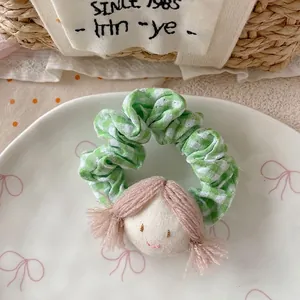 Detail of green plaid fabric scrunchie with cute girl doll on a white ceramic plate
